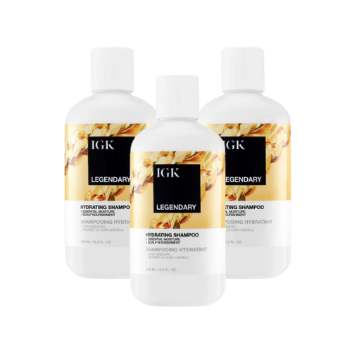 Three bottles of IGK Legendary Hydrating Shampoo with floral design labels.
