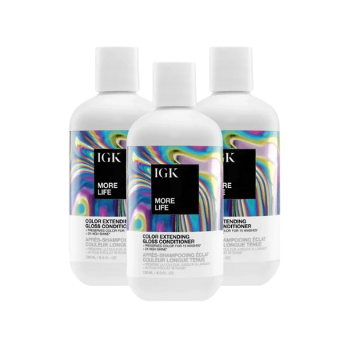 Three bottles of IGK More Life Color Extending Gloss Conditioner with colorful labels.